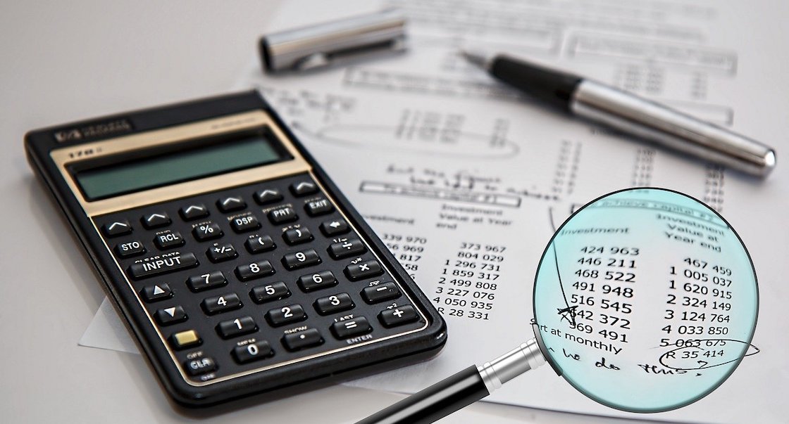 Calculator, pen, and magnifying glass on bank statements.
