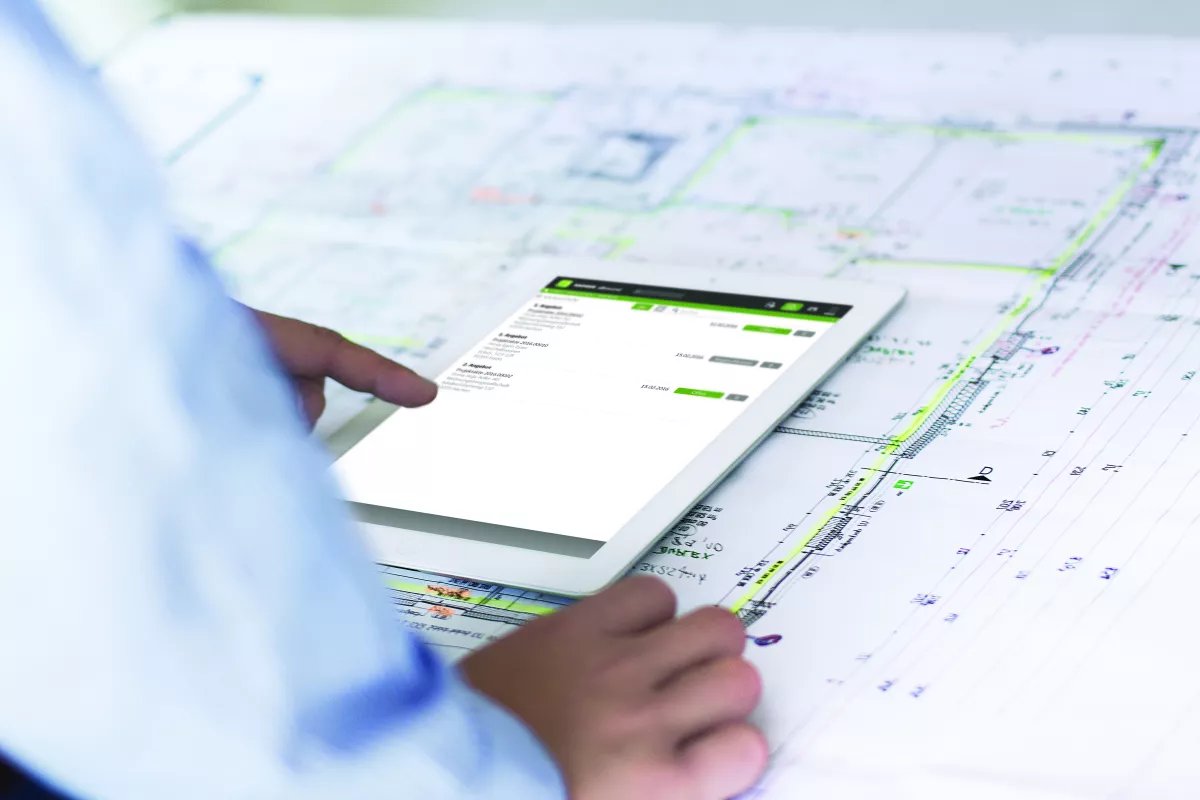 Tablet displaying invoice data over architectural plans.