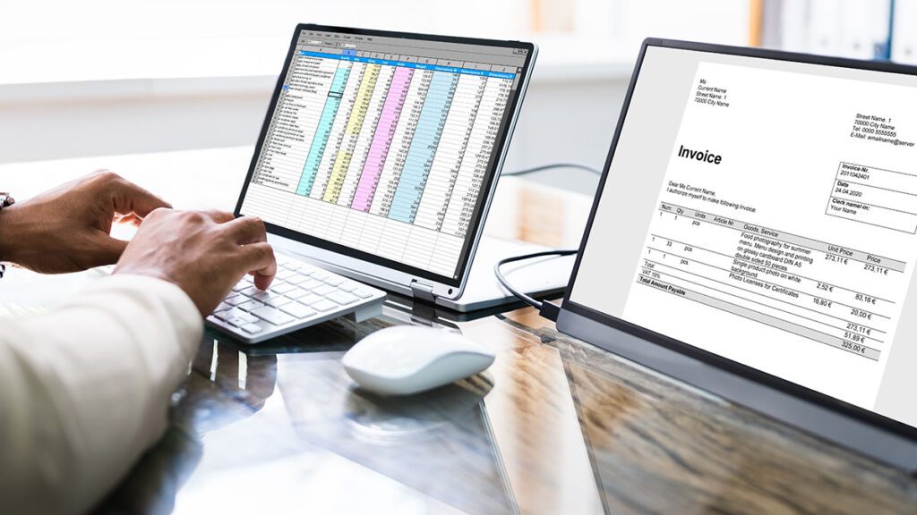 Person using a computer to process invoices and spreadsheets.